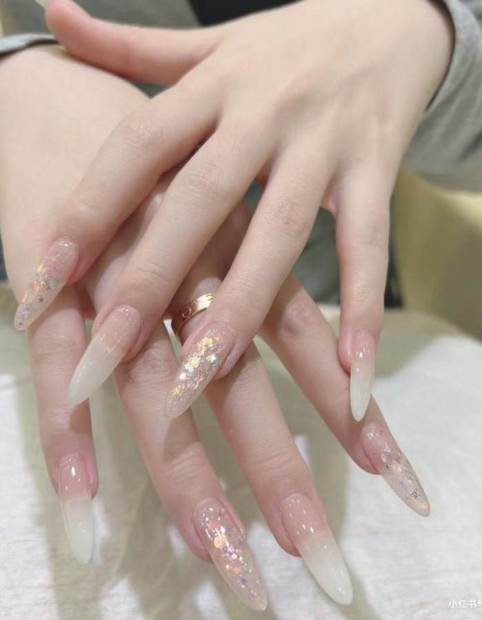 Clear jelly nails covered with glitter and luxurious stones