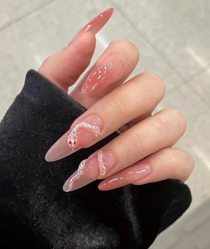 Clear pink rounded pointed nail design with luxurious snake motifs