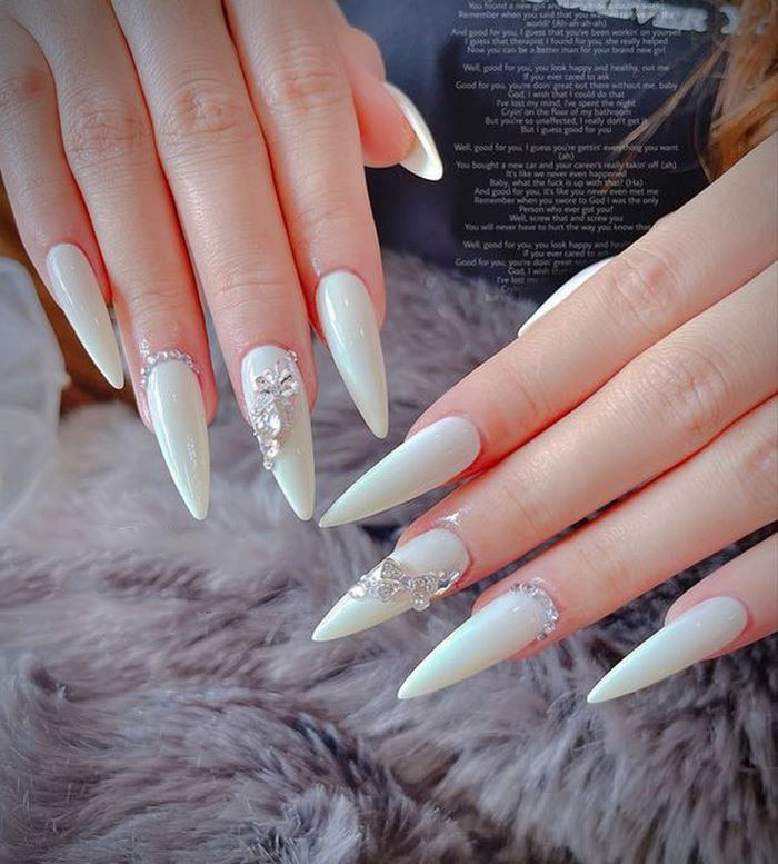 Suggesting pointed opaque white nails with striking stones