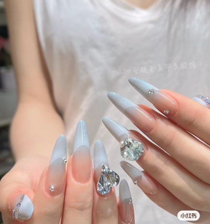 Suggested pointed nail design in pale blue mixed with pink and studded with stones