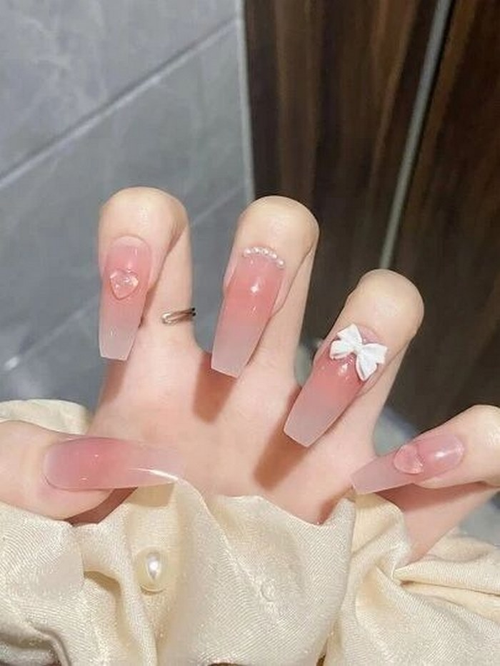 Pink nail design uses white bows and super pretty bead charms