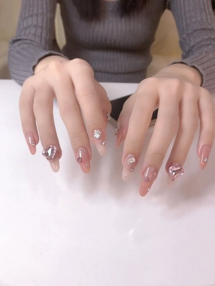 Pink rhinestone nails with stones create a unique style for her