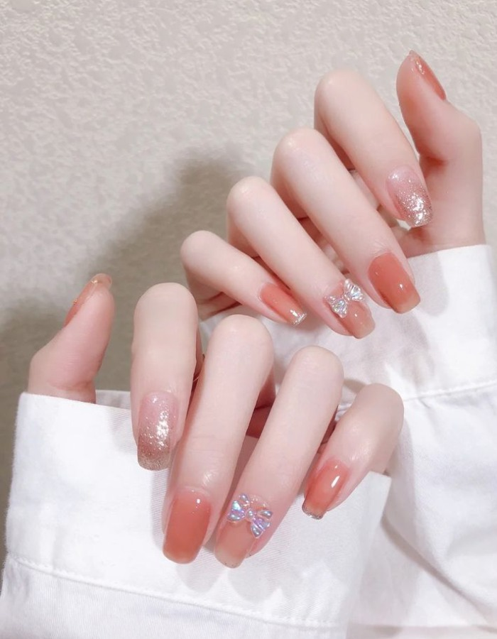 Orange white jelly nail design with cute glitter-covered bow